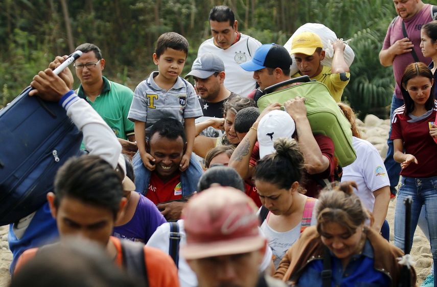 Un grupo de venezolanos cruza con sus pertenencias hacia territorio de Cúcuta,&nbsp;Colombia, atravesando un río debido al cierre de los pasos fronterizos.