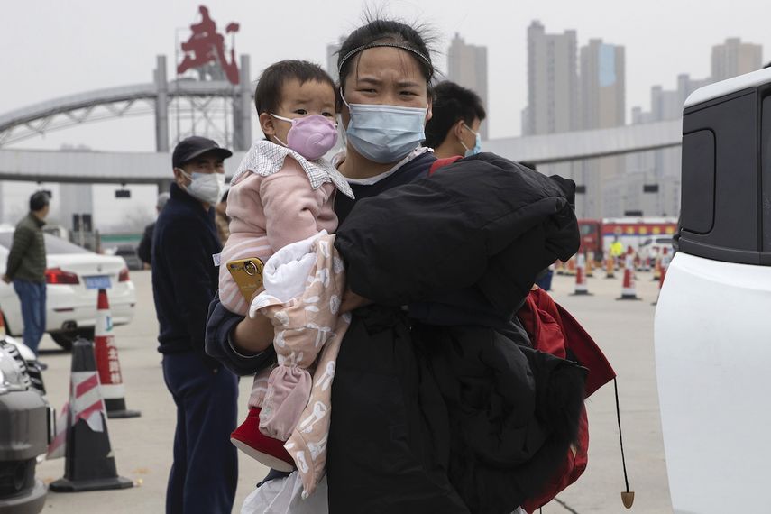 En esta imagen, tomada el 2 de abril de 2020, una mujer con una ni&ntilde;a en brazos se aleja de una carretera en la frontera de la ciudad de Wuhan, en la provincia de Hubei, en el centro de China.&nbsp;