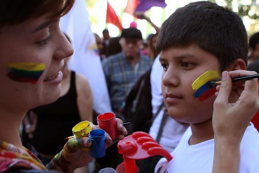 Una mujer pinta con los colores de la bandera de Colombia la mejilla de un niño durante un acto para celebrar acuerdo de cese el fuego y dejación de armas entre el Gobierno colombiano y la guerrilla de las Fuerzas Armadas Revolucionarias (FARC) (