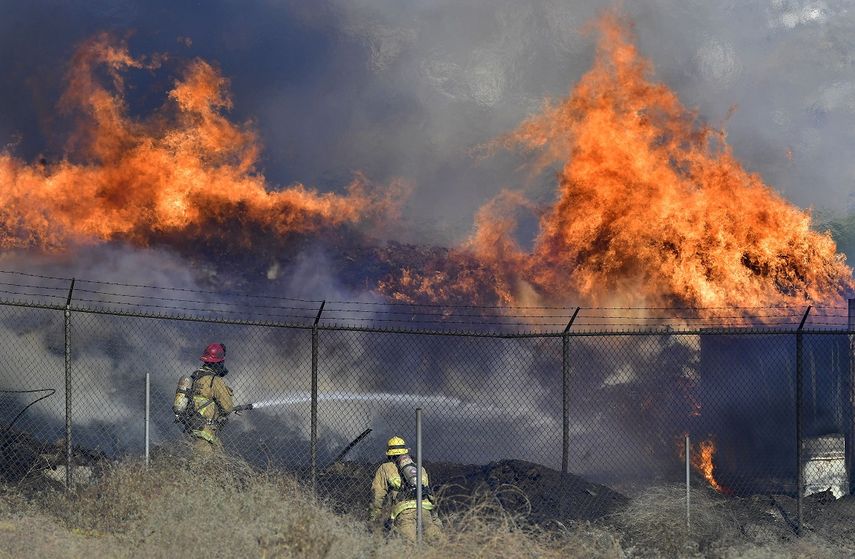 Dos bomberos combaten un incendio que arde fuera de control el jueves 3 de diciembre de 2020, en Riverside, California.&nbsp;