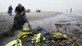 El socorrista Robert Butler recoge en una bolsa chalecos salvavidas que se encuentran cerca de uno de dos botes que se volcaron cuando transportaban a migrnates en aguas poco profundas pero turbulentas frente a Blacks Beach, en la costa de San Diego, el 12 de marzo de 2023.&nbsp;