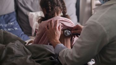 Una doctora ausculta los pulmones de una niña menor de seis años.