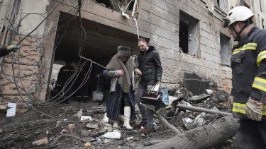 Un hombre ayuda a una mujer a salir de un edificio residencial alcanzado por un cohete ruso en el centro de Járkiv, Ucrania, el domingo 5 de febrero de 2023.&nbsp;