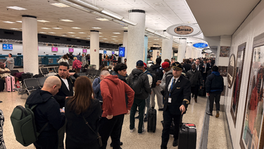 Fila de pasajeros en Aeropuerto Internacional de Miami esperando pasar el control de seguridad.