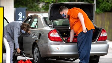 Dos personas rellenan con gasolina varios envases.&nbsp;