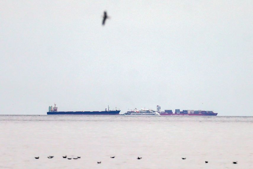 El crucero australiano Greg Mortimer, al centro, es rodeado por dos buques de carga frente al puerto de Montevideo, Uruguay, el domingo 5 de abril de 2020. De 217 personas entre pasajeros y tripulantes sometidos a pruebas a bordo del crucero, 128 dieron positivos por coronavirus, seg&uacute;n Aurora Expeditions, organizadora del viaje.&nbsp;