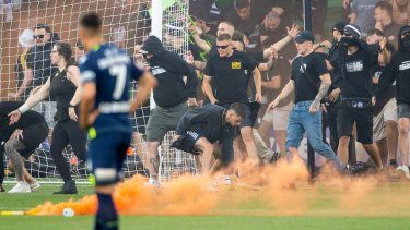 Fans del equipo Melbourne Victory invaden la cancha durante un partido de la Liga A australiana entre Melbourne City y Melbourne Victory en el estadio AAMI Park, el sábado 17 de diciembre de 2022. Los fanáticos atacaron al portero del City, Tom Glover, y el partido fue suspendido.