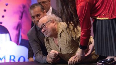 DeVito se encaminó hacia el escenario donde debía subir cuatro escalones y en el último no levantó demasiado su pie derecho, tropezó y cayó con el peso de su cuerpo sobre el brazo izquierdo.