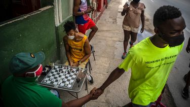 Personas con máscaras como precaución contra la propagación del nuevo coronavirus caminan por una calle mientras otros juegan al ajedrez en una acera en La Habana, Cuba, el miércoles 23 de septiembre de 2020. Estados Unidos agregó el lunes 28 de septiembre de 2020 a su lista negra para operar con Cuba a una tarjeta de débito que en los últimos meses se volvió popular en la isla porque les permite a los ciudadanos comprar electrodomésticos, piezas de repuestos y alimentos.