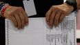 Un funcionario del Departamento de elecciones manipula boletas.