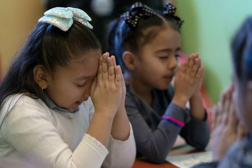 Gaby Meza Rodriguez, de 7 años, a la izquierda, reza con otros niños durante una sesión de la escuela dominical mientras sus padres asisten a un servicio religioso, el domingo 17 de diciembre de 2023 en Fort Morgan, Colorado. Los padres de Meza Rodriguez, que tienen cuatro hijos nacidos en Estados Unidos, incluida ella, están en un limbo legal mientras solicitan un permiso de residencia.