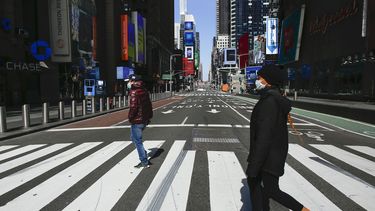 La gente usa una m&aacute;scara facial mientras cruzan una calle en Times Square el 22 de marzo de 2020 en la ciudad de Nueva York.&nbsp; 