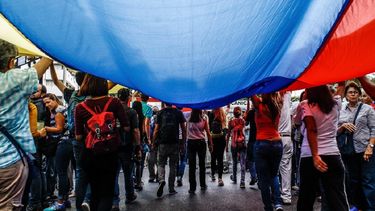Venezolanos marchan en Caracas con la bandera de Venezuela.