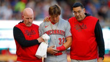 Tyler Callihan #32 de los Cincinnati Reds recibe ayuda para salir del campo tras chocar contra la barda durante la tercera entrada contra los Atlanta Braves en el Truist Park el 5 de mayo de 2025 en Atlanta, Georgia.&nbsp;