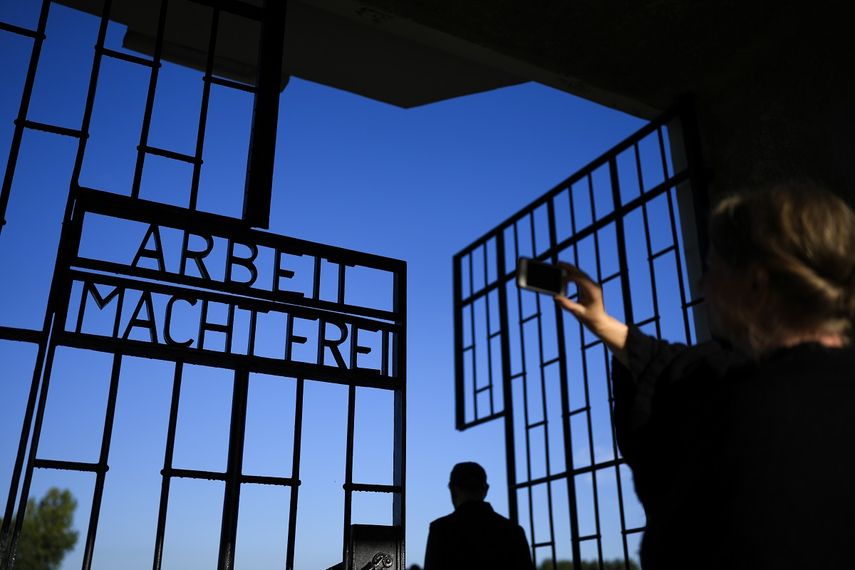Una mujer toma una foto en la entrada del antiguo campo de concentración nazi de Sachsenhausen,al que se accede cruzando una cerca con la frase en alemán Arbeit macht frei (El trabajo te hace libre), en Oranienburg, Alemania, el 6 de octubre de 2021.&nbsp;