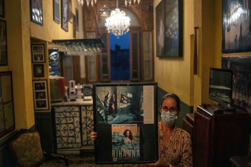 Una trabajadora del restaurante La Guarida, con una máscara como medida de precaución en medio de la propagación del COVID-19, posa con fotos de la cantante Rihanna en La Habana, Cuba, el miércoles 3 de noviembre de 2021.