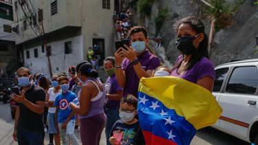Varias personas usando tapabocas ven pasar la imagen del Nazareno en la Semana Santa, en Caracas, Venezuela, durante la cuarentena por el coronavirus COVID-19.