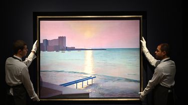 En esta foto de archivo tomada el 6 de octubre de 2022, los asistentes de la galería sostienen el cuadro titulado Early morning, Sainte-Maxime, 1968-69 del pintor británico David Hockney durante una sesión fotográfica para 20th/21st Century: London Evening Sale at Christies en Londres.