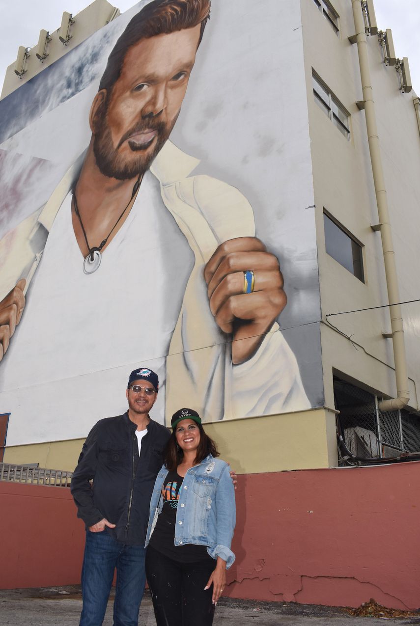 Willy Chirino y Alexandra Seda posan junto al mural en honor al cantautor.&nbsp;