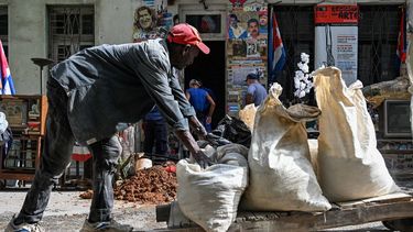 Un hombre transporta objetos cerca de una casa que muestra un cartel del depuesto dictador venezolano Nicolás Maduro y del fallecido Hugo Chávez, en La Habana el 14 de enero de 2026.