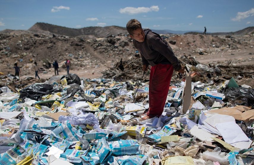 Ronaikel Brito, de 16 años, hurga en cartones de leche vacíos en el basurero de Pavia en las afueras de Barquisimeto, Venezuela, el miércoles 3 de marzo de 2021.&nbsp;