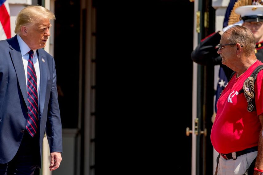 El presidente Donald Trump con Terry Sharpe, un exinfante de marina que hace un recorrido a pie hacia la Casa Blanca todos los años para llamar atención al problema de suicidios entre veteranos, en la Casa Blanca en Washington, el 27 de julio del 2020.