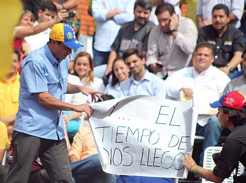 Capriles en su campaña presidencial repetía que el tiempo de Dios es perfecto, un partidario entrega un afiche con la inscripción El tiempo de Dios llegó(PRENSA CAPRILES)