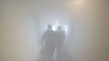 Una pareja con mascarilla pasa por una sala de descontaminaci&oacute;n como medida de precauci&oacute;n contra la propagaci&oacute;n del coronavirus antes de entrar a una tienda, en Caracas, Venezuela.