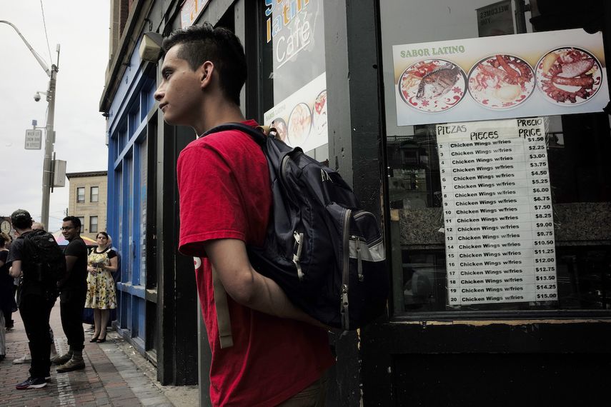 En esta fotografía del domingo 30 de junio de 2019 unas personas se preparan para abordar un autobús frente a un restaurante latino en Chelsea, Massachusetts.