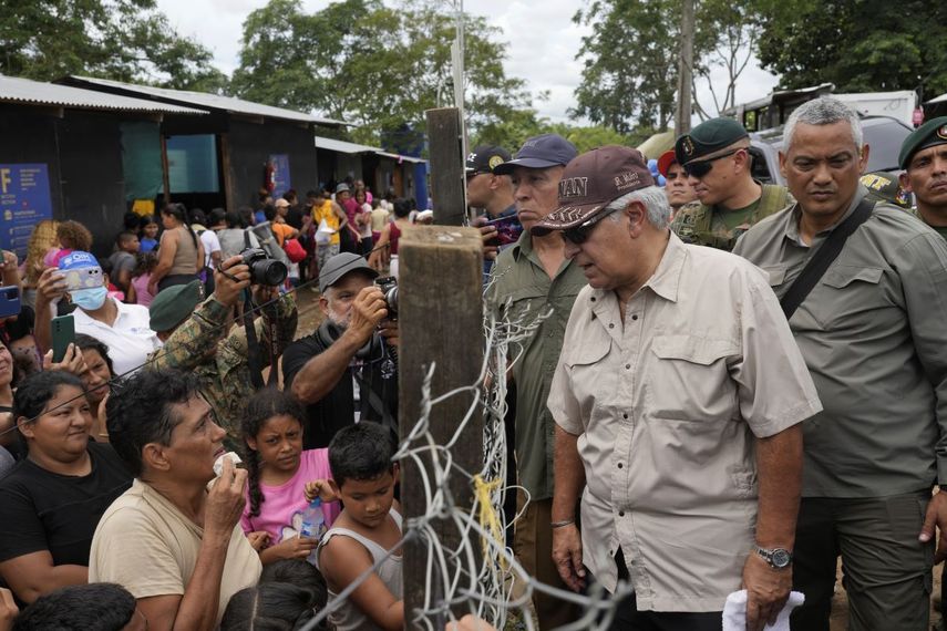 El presidente panameño, José Raúl Mulino, habla con un migrante venezolano, a la izquierda, y otros migrantes en un campamento después de que cruzaran caminando el Tapón del Darién desde Colombia, en Lajas Blancas, Panamá, el viernes 28 de junio de 2024.