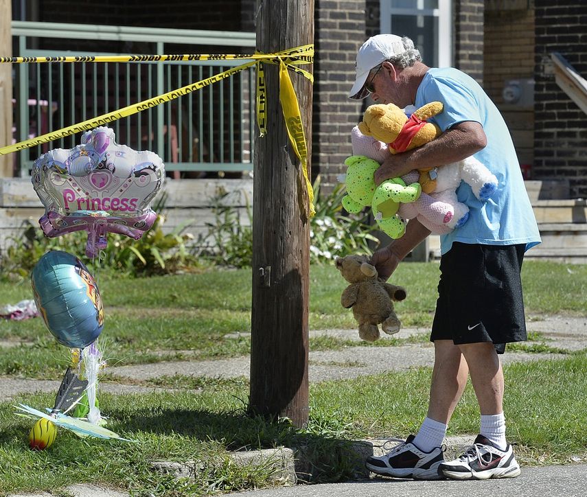 Paul Laughlin, de 57 años, coloca animales de peluche afuera de una casa en Erie, Pensilvania, donde varias personas murieron durante un incendio la mañana del domingo 11 de agosto de 2019.