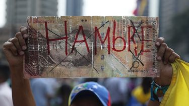 Una mujer muestra un billete de cien bolívares a gran escala con la palabra hambre durante una manifestación opositora en Caracas, Venezuela, este 10 de abril de 2019.