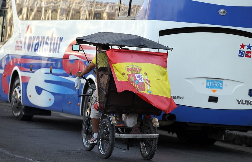 Un bicitaxi recorre calles de La Habana, Cuba, con la bandera de España.