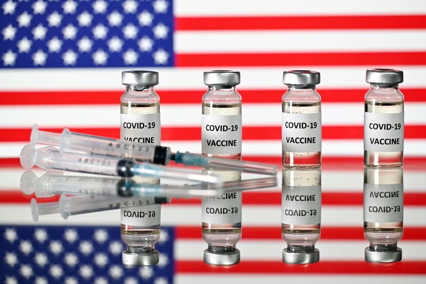 Una imagen ilustrativa muestra frascos de la vacuna COVID-19 y jeringas, con una bandera de los Estados Unidos.