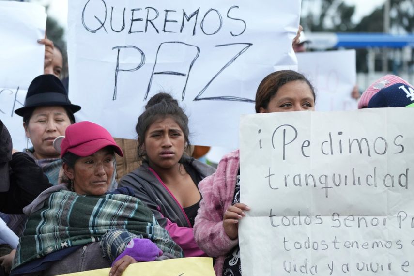 Familiares de reclusos sostienen carteles pidiendo paz mientras protestan frente a la prisión de Latacunga.