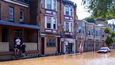 Tres personas miran una calle inundada tras el desbordamiento del río Schuylkill, el jueves 2 de septiembre de 2021, en el sector East Falls de Filadelfia.&nbsp;