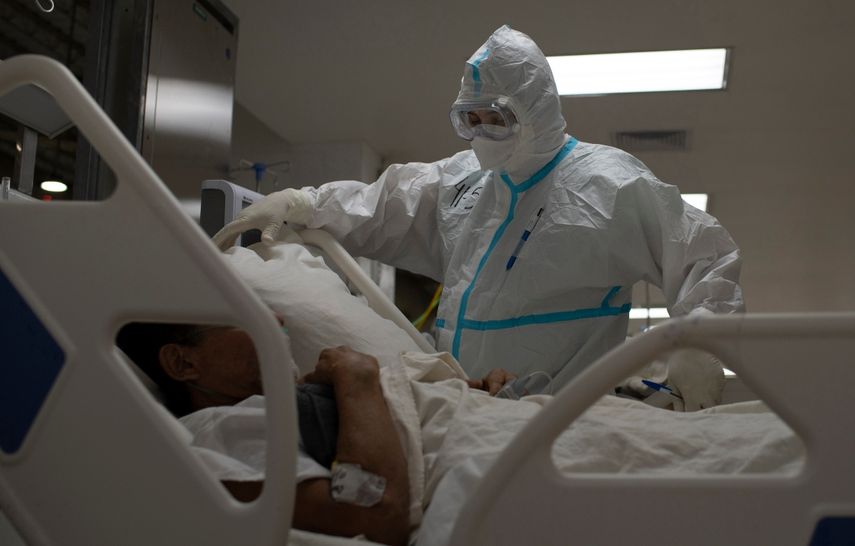Un trabajador sanitario español y voluntario de la Fundación SAMU atiende a un paciente salvadoreño que sufre una crisis respiratoria por el nuevo coronavirus, COVID-19, en la unidad de cuidados intensivos del Hospital El Salvador, en San Salvador, el 12 de agosto de 2020.