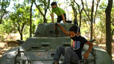 Niños con máscaras protectoras juegan en un vehículo blindado que se exhibe en Caracas, Venezuela, el domingo 26 de abril de 2020. El gobierno de Venezuela permitió que los niños salieran durante ocho horas después de que impusiera una cuarentena para evitar la propagación del nuevo coronavirus.