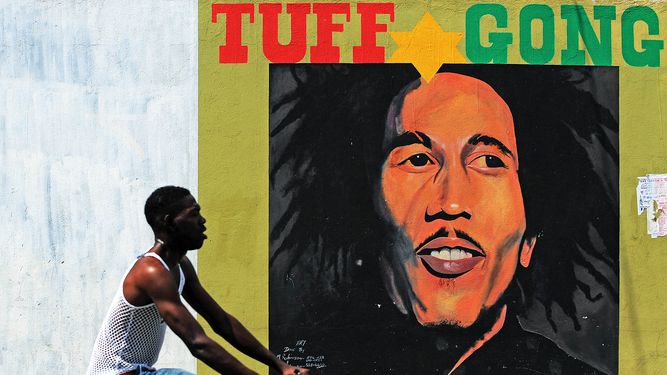 En esta foto de archivo tomada el 8 de febrero de 2009, un hombre pasa junto a un mural del fallecido músico Bob Marley en Kingston.