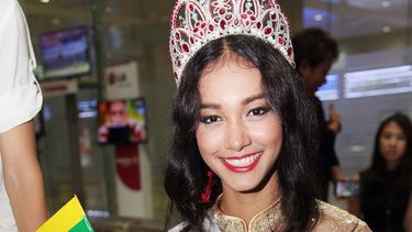 La modelo de Mianmar May Myat Noe, ganadora del certamen Miss Asia Pacífico Mundo 2014, ondea una pequeña bandera de su país a su llegada al aeropuerto internacional en Yangon, Mianmar. (AP)