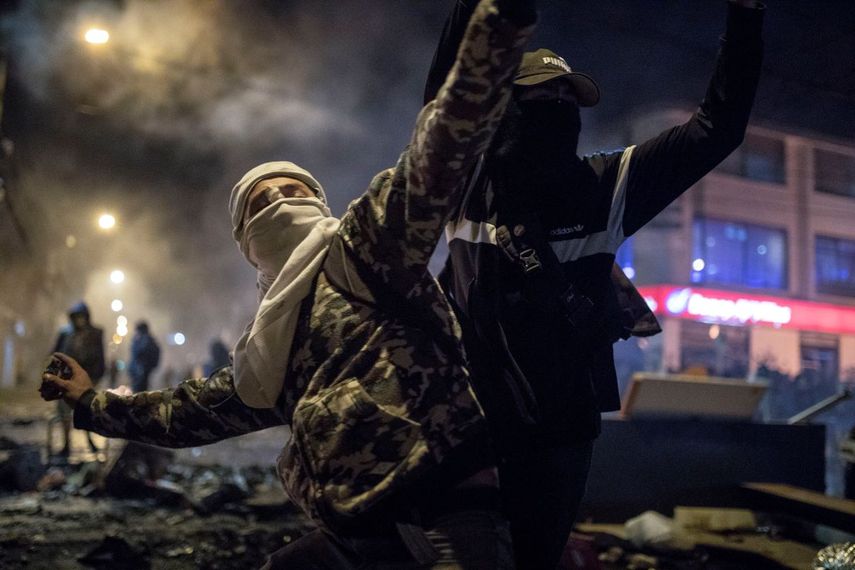 &nbsp; Un hombre con m&aacute;scara y capucha arroja piedras a la polic&iacute;a el jueves 10 de septiembre de 2020 durante protestas por la muerte de un hombre a manos de la polic&iacute;a, en Bogot&aacute;, Colombia.&nbsp; &nbsp;