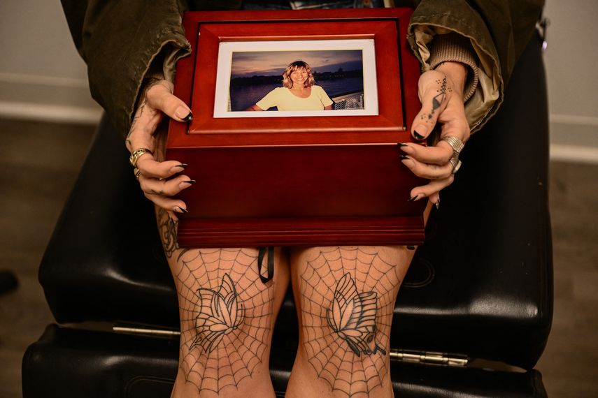 Scout Frank sostiene una caja con las cenizas de su madre cremada, Theresa Pendleton, antes de recibir un tatuaje hecho a mano por la artista Kat Dukes usando tinta mezclada con las cenizas en Oceanside, California, el 6 de octubre de 2023.