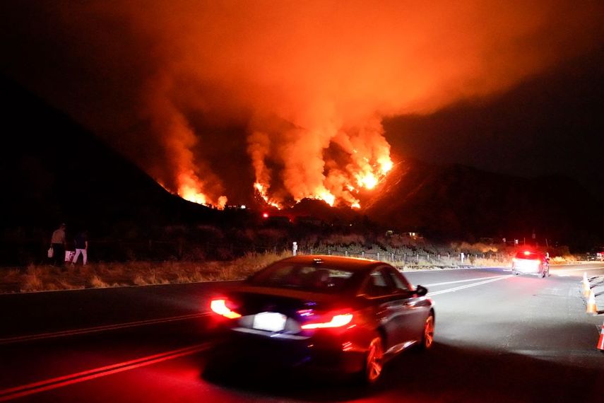  Conductores se abren paso en una carretera en una zona de incendios, el jueves 13 de agosto de 2020, en Azusa, California.