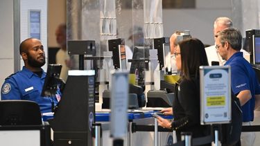 Oficial de la TSA verificando los documentos de identidad de los pasajeros en un punto de control de seguridad en el Aeropuerto Nacional Ronald Reagan, en Arlington, Virginia.