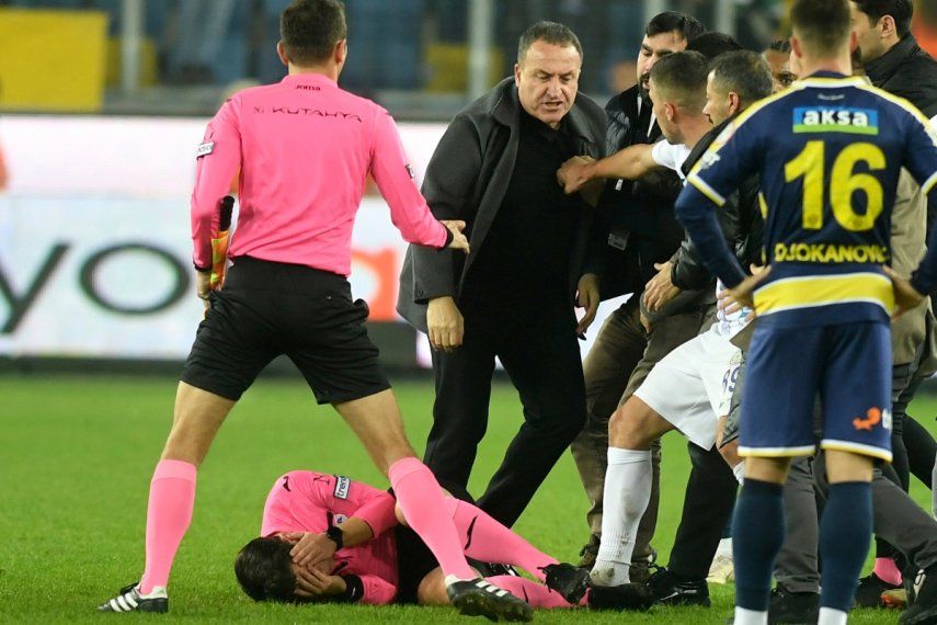 En esta imagen de archivo, el árbitro Halil Umut Meler se sujeta el rostro mientras está tirado sobre el piso luego de recibir un golpe del presidente del MKE Ankaragucu, Faruk Koca (centro), al final de un partido de la Superliga turca frente al Caykur Rizespor, en Ankara, el 11 de diciembre de 2023.&nbsp;