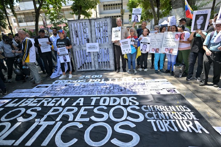 Manifestantes llevan pancartas en contra del régimen de Nicolás Maduro y exijen la libertad para los presos políticos en una protesta ante la Embajada de Brasil en Caracas.