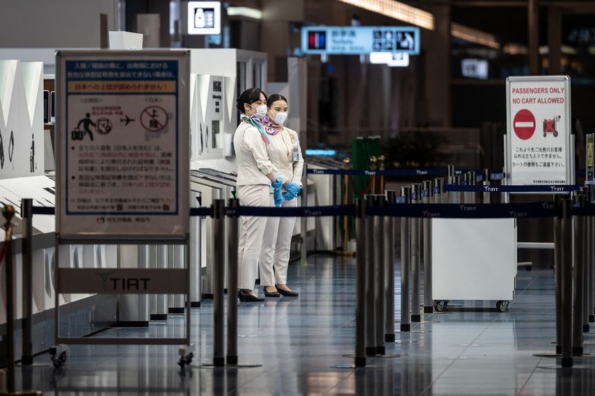 Los miembros del personal se paran en la puerta de salida del aeropuerto internacional Haneda de Tokio el 29 de noviembre de 2021, cuando Japón anunció planes para prohibir a todos los nuevos viajeros extranjeros sobre la variante Omicron de COVID-19. &nbsp;