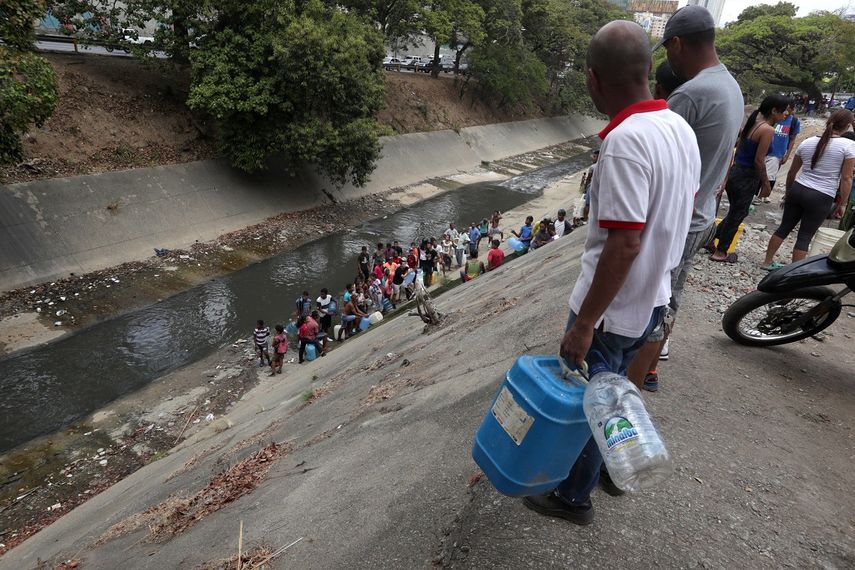Decenas de personas recogen agua el lunes 11 de marzo en las márgenes del río Guaire, en las inmediaciones de la autopista Francisco Fajardo, en Caracas, Venezuela.