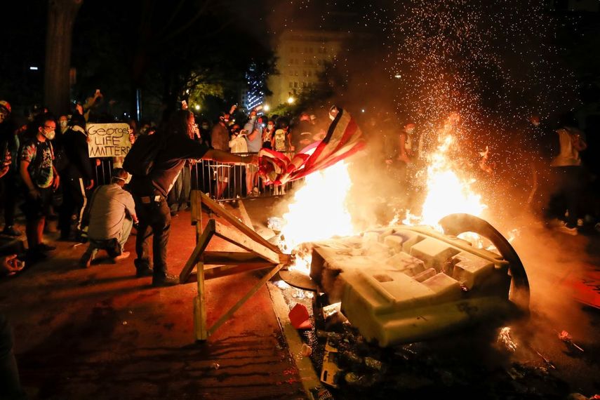 Manifestantes prenden un fuego durante una protesta por la muerte de George Floyd, y queman una bandera de Estados Unidos, el domingo 31 de mayo de 2020 en Washington. Las protestas se han tornado violentas causando destrucci&oacute;n y saqueos en el pa&iacute;s.