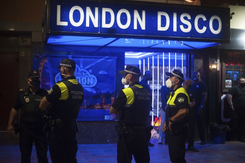 Polic&iacute;as con mascarillas vigilan mientras personas caminan en la calle en Fuengirola, cerca de M&aacute;laga, Espa&ntilde;a, el s&aacute;bado 8 de agosto de 2020.&nbsp;